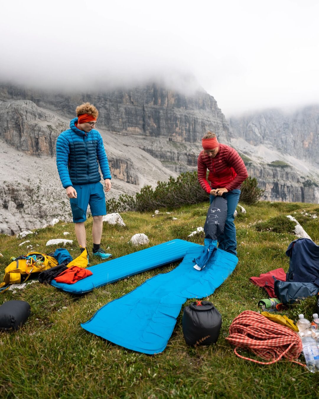 Bergsportler mit Schlafmatten und Biwakausrüstung auf einer Bergwiese