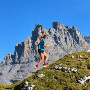 Trailrunnerin auf einem alpinen Bergweg vor markanten Felsgipfeln bei Engelberg