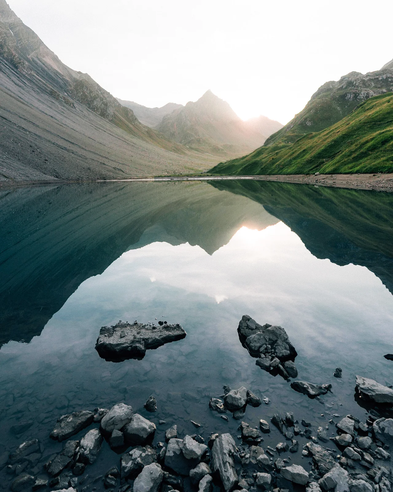 Bergsee zwischen steilen Bergflanken im Abendlicht