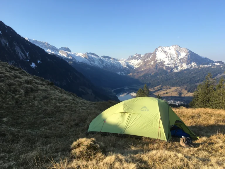 How to Biwak – mit POW eine Nacht draussen | Samstag & Sonntag Grünes Biwakzelt auf einer Bergwiese mit Blick auf die umliegenden Gipfel