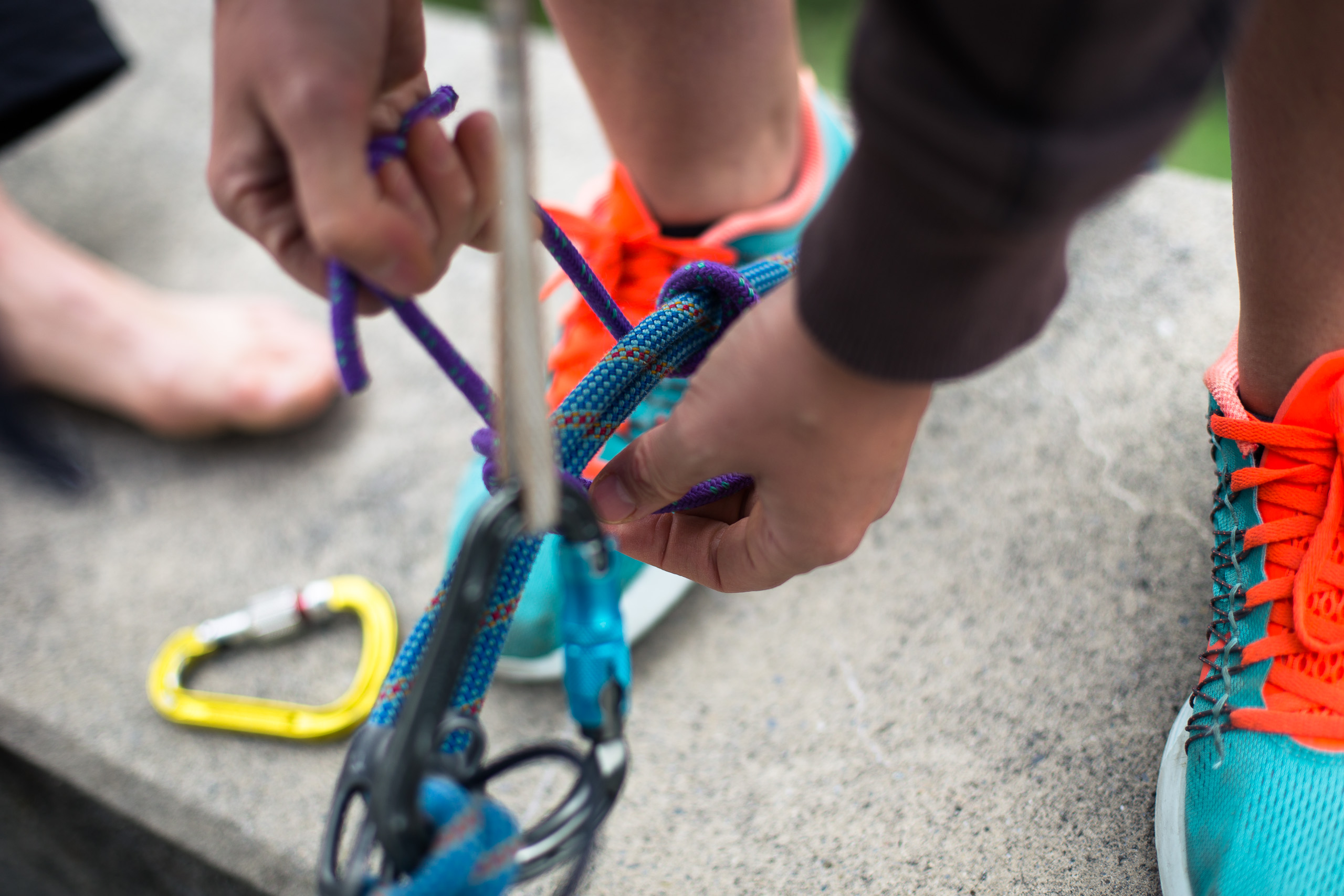 Hände üben einen Seilknoten mit Karabiner bei der Kletterausbildung